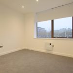 Empty room with large window and carpeted floor.
