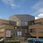 Office building with large windows and parked cars.