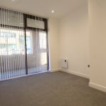Bright empty room with large window and vertical blinds.