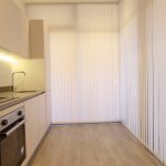 Modern kitchen with blinds and wooden floor.