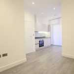 Modern minimalist kitchen with white cabinets and flooring.