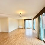 Spacious empty room with wooden floor and large windows.