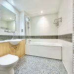 Modern bathroom with white tiles and wooden cabinetry.