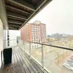 Residential balcony overlooking cityscape and parked cars.