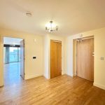 Spacious hallway with wooden flooring and doors.