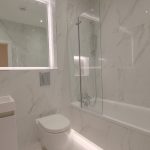Modern bathroom with marble tiles and illuminated mirror