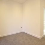 Empty room with light walls and grey carpet.