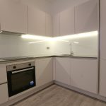 Modern kitchen with sleek white cabinets and lighting.