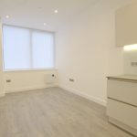 Minimalist kitchen with wooden flooring and large window.