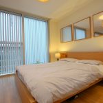 Modern bedroom with wooden furniture and large windows.
