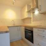 Modern kitchen with wooden countertops and white cabinets.