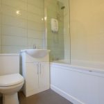 Modern bathroom with shower and tiled walls.