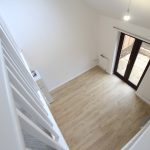 Modern living room with wooden flooring and stairs.