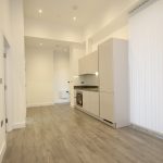 Modern kitchen with wooden flooring and white cabinets.