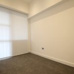 Empty room with vertical blinds and carpet flooring.