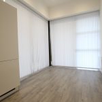 Empty room with wooden floor and vertical blinds.