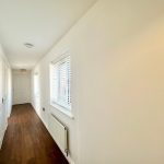 Bright hallway with wooden floor and white walls.