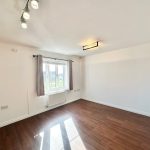 Bright empty room with wooden flooring and window.