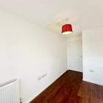 Empty room with wooden floor and red lampshade.