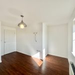 Bright empty room with wooden flooring and pendant light.