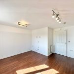 Bright empty room with wood floor and spotlights.