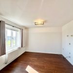 Empty room with wooden floor and window view.