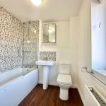 Modern bathroom with tiled walls and white fixtures.