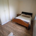 Small bedroom with wooden bed and wardrobe.
