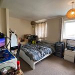 Cluttered bedroom with computer setup and tools.