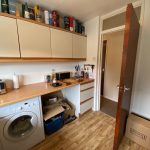 Laundry room with washer and wooden cabinets.