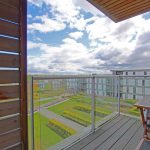 Modern balcony with scenic view over apartments and gardens.
