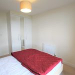 Modern bedroom with red bedding and wardrobe