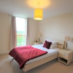 Cosy bedroom with red bedding and large window.
