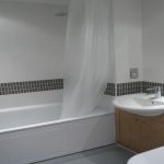 Modern bathroom with tub, sink, and tiled walls.