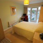 Cosy bedroom with desk and large window view.