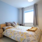 Cosy bedroom with geometric bedding and pillows.