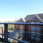 View from balcony overlooking modern red-brick buildings.
