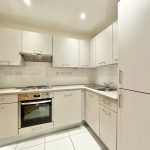 Modern white kitchen with oven and cabinets.
