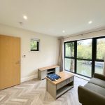 Modern room with large windows and wooden furniture.