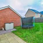 Back garden with trampoline and brick wall.