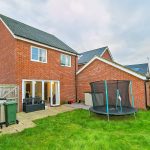 Brick house with trampoline and patio in garden