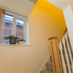 Indoor staircase with wooden railing and window plants
