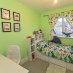 Child's room with dinosaur decor and green walls.