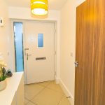 Bright hallway with wooden doors and orchid plant.