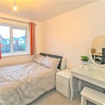 Cosy bedroom with bed, window, and dressing table.