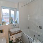Modern bathroom with sink, bathtub, and window.