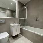 Modern bathroom with bathtub and vanity unit.