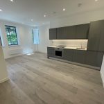 Modern empty kitchen with grey cabinets and wooden floor