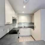 Modern white kitchen with grey countertops and cabinets.