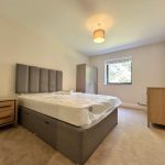 Modern bedroom with bed, wardrobe, and window view.
